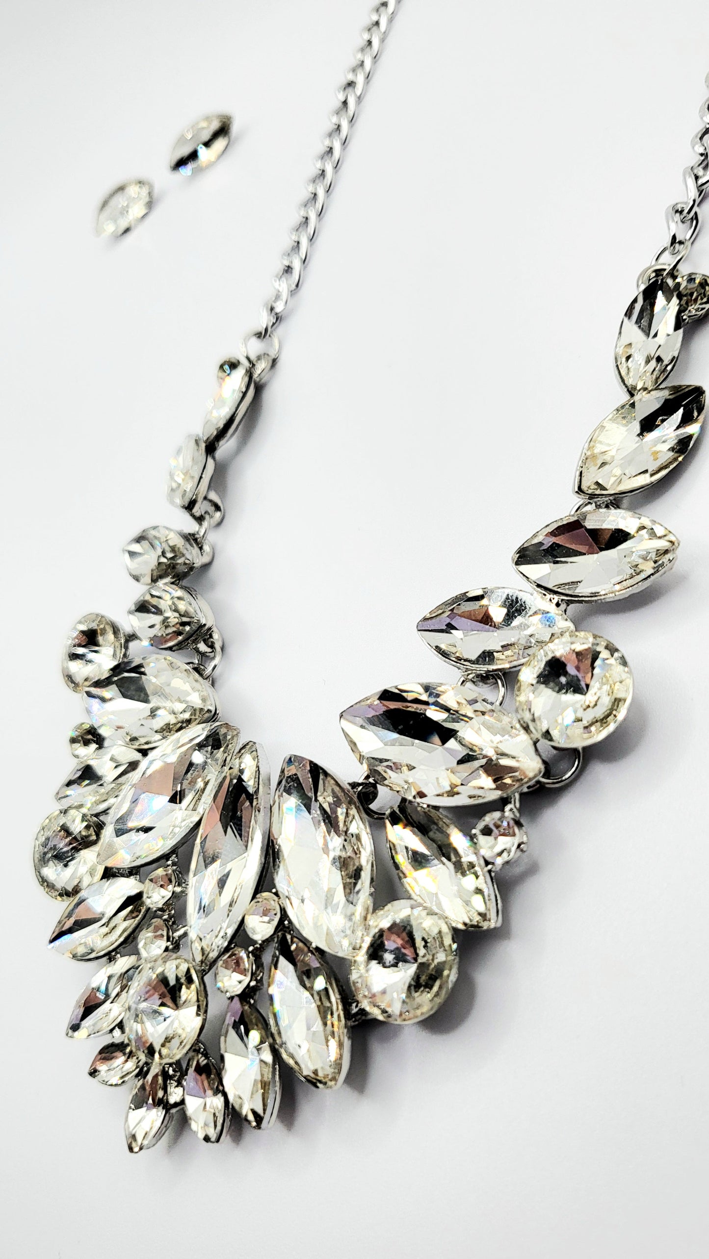 Silver necklace with clear gemstones on a white background
